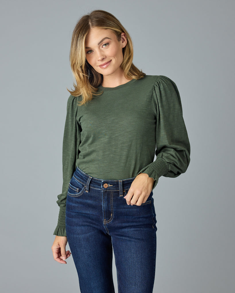 Woman in a green, long sleeve tshirt with ruffle details on sleeve