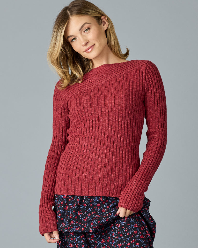 Woman in a red, long sleeve sweater with cable detailing