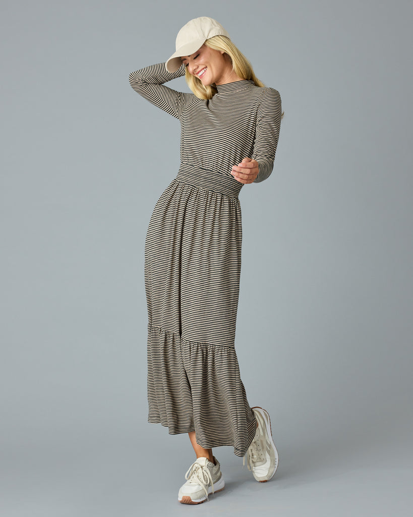 Woman in a black and tan thin striped maxi dress with long sleeves, a mock neck and pockets