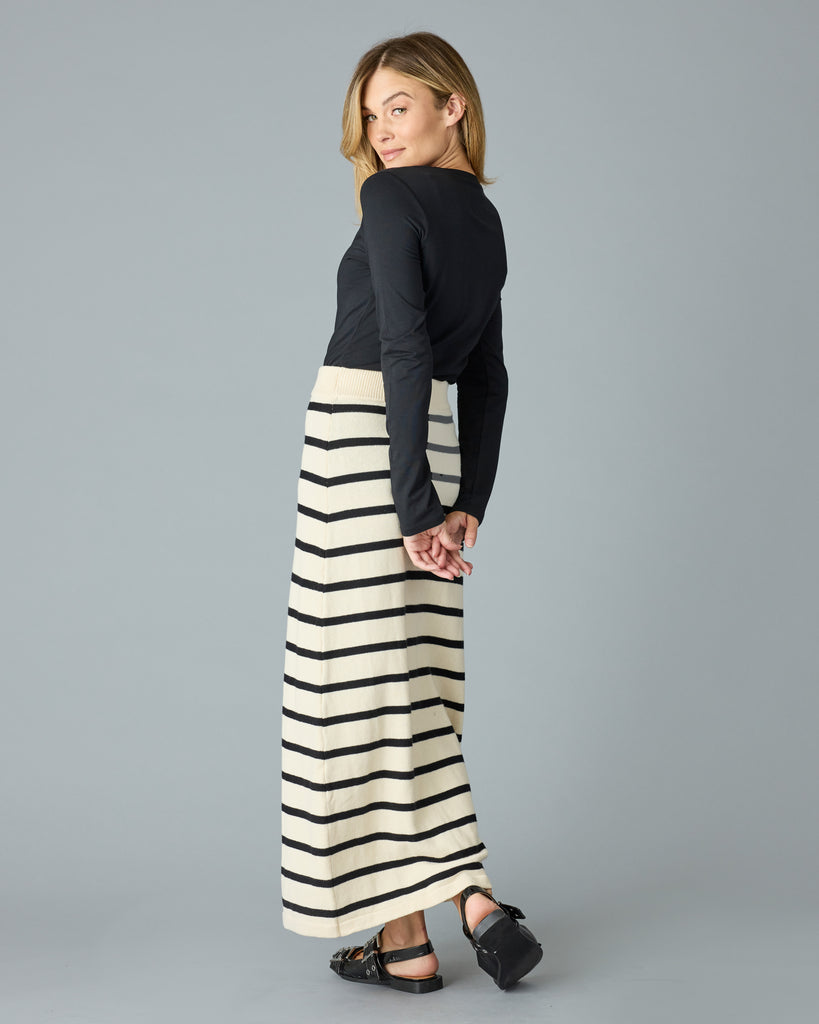 Woman in a black and tan striped maxi sweater skirt with a black top