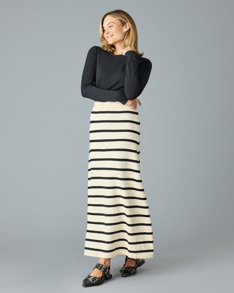 Woman in a black and tan striped maxi sweater skirt with a black top