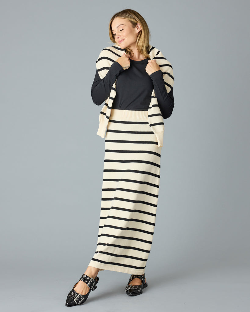 Woman in a black and tan striped maxi sweater skirt with a black top