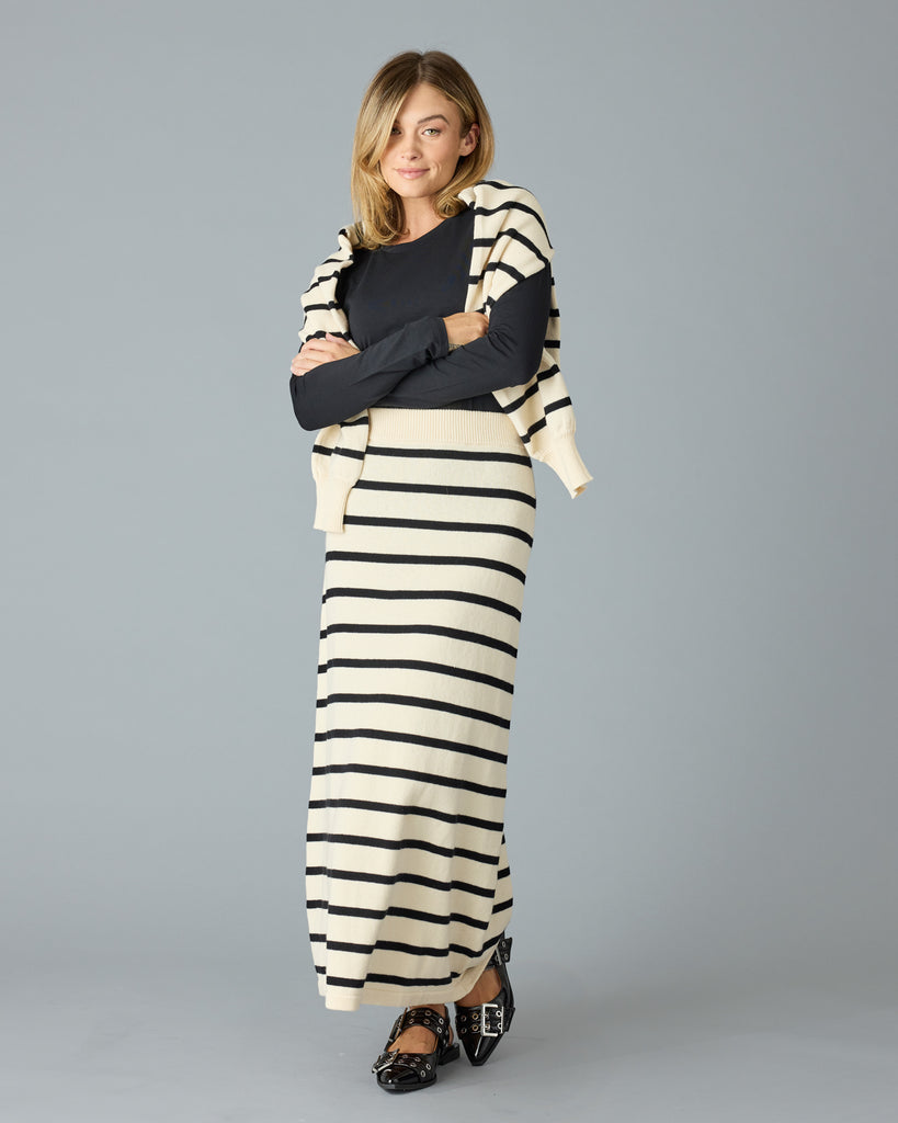 Woman in a black and tan striped maxi sweater skirt with a black top