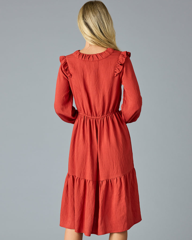 Woman in a red, long sleeve, v-neck, midi dress with ruffles down the front