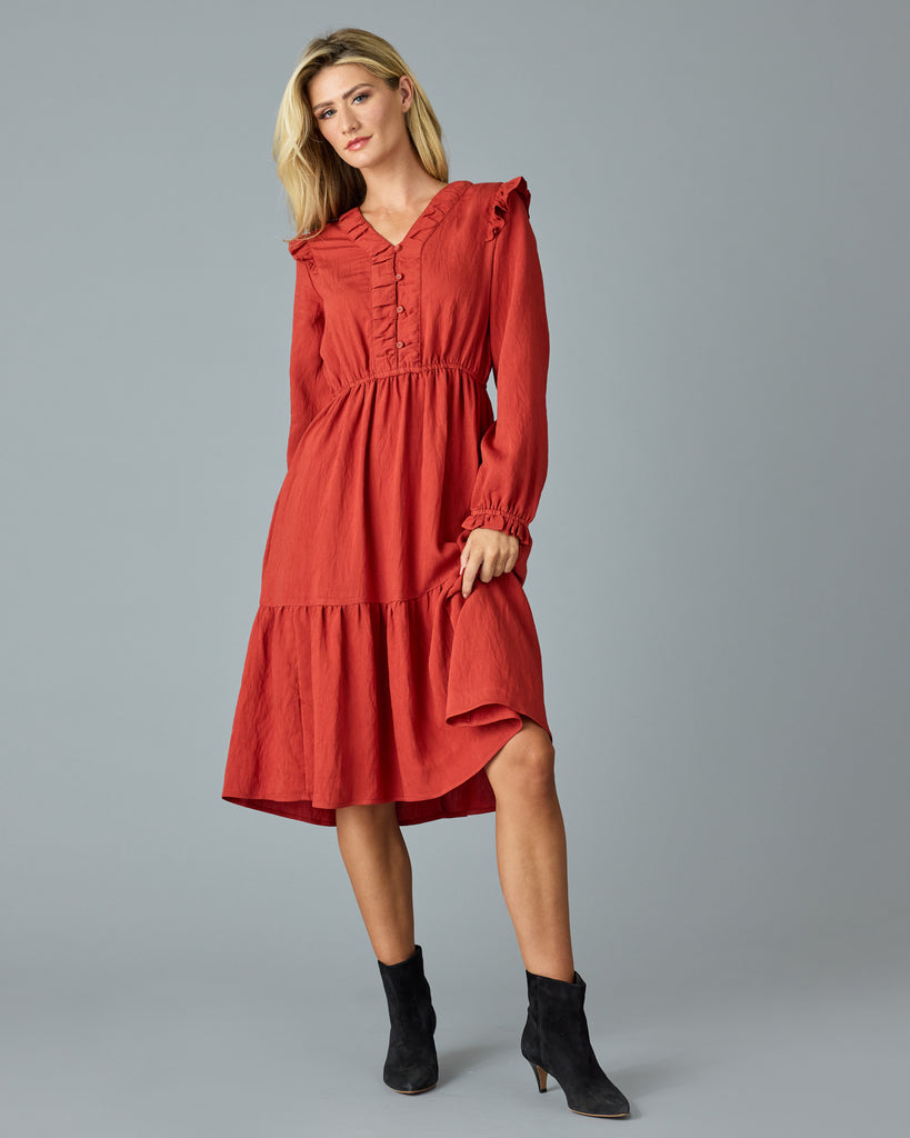 Woman in a red, long sleeve, v-neck, midi dress with ruffles down the front