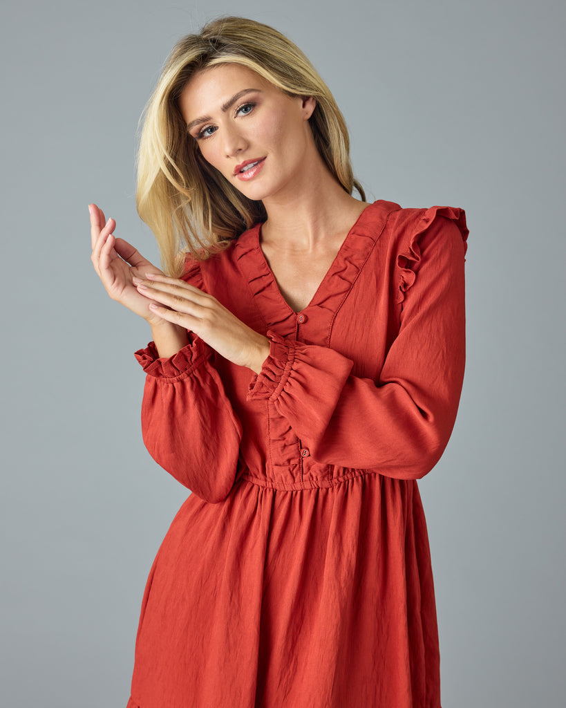 Woman in a red, long sleeve, v-neck, midi dress with ruffles down the front