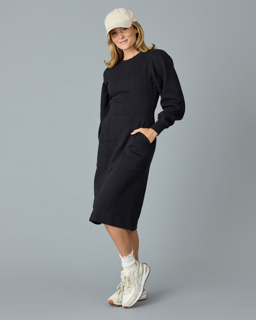 Woman in a black, long sleeve, midi length sweater dress