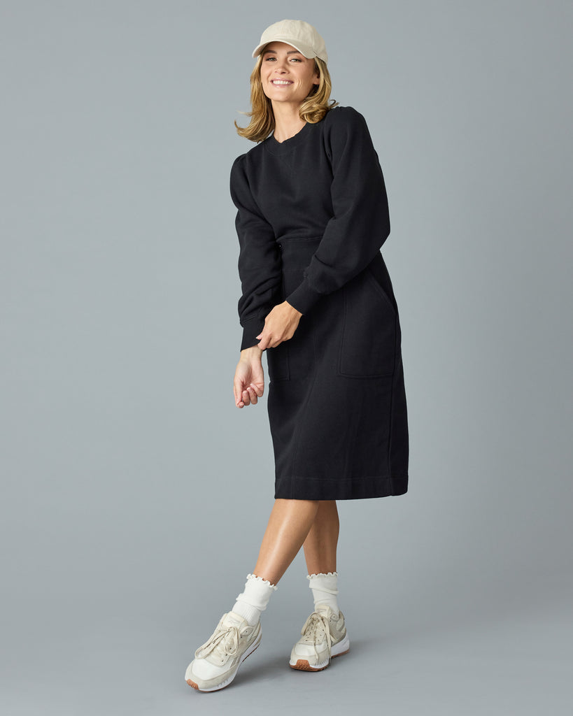 Woman in a black, long sleeve, midi length sweater dress