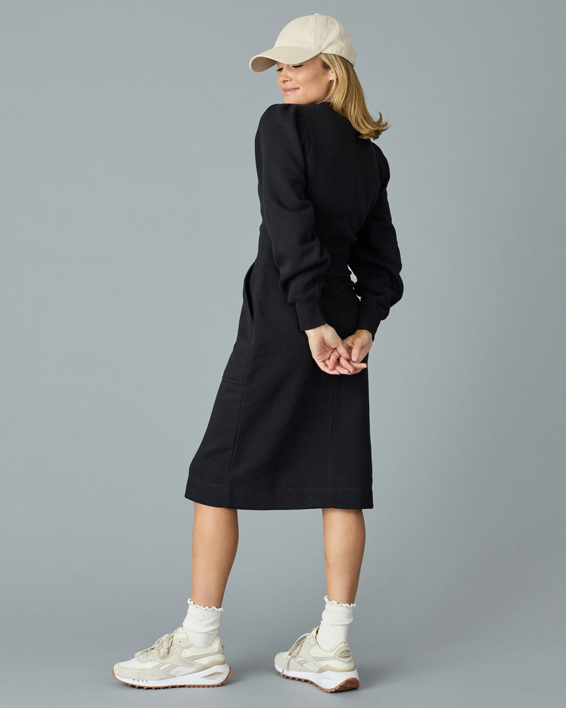 Woman in a black, long sleeve, midi length sweater dress