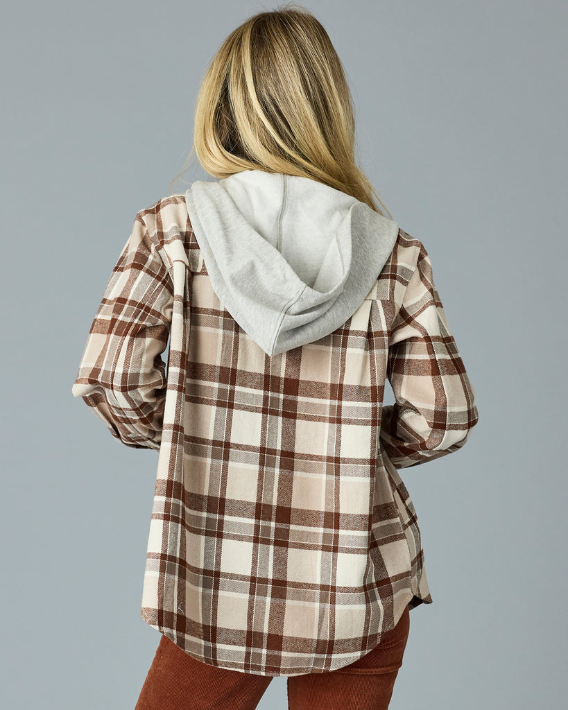 Woman in a tan plaid buttondown with a sweater hood attached