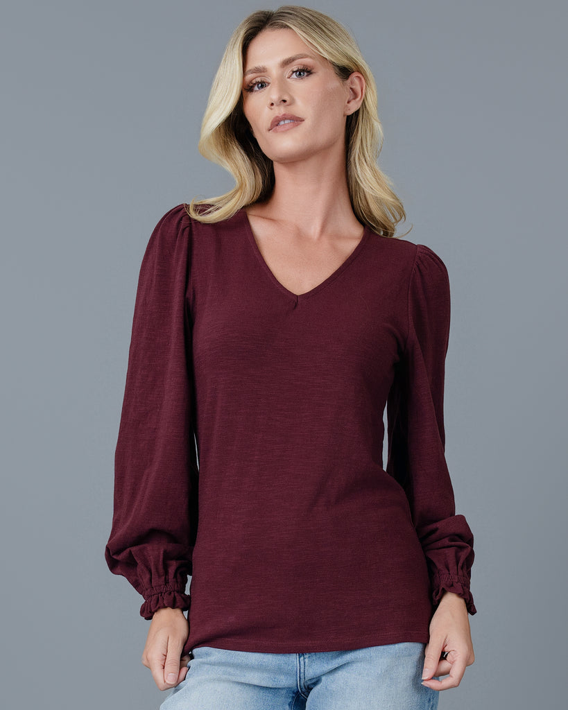 Model wearing a burgundy long balloon sleeve, v-neck knit top.