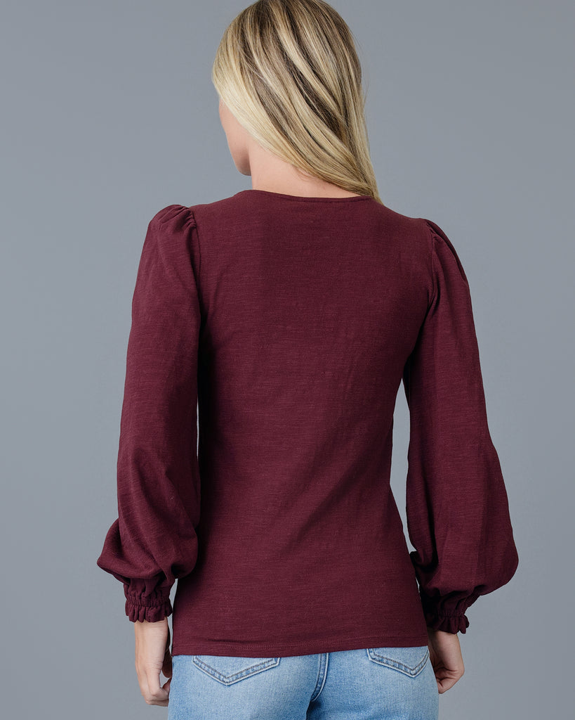 Model wearing a burgundy long balloon sleeve, v-neck knit top.