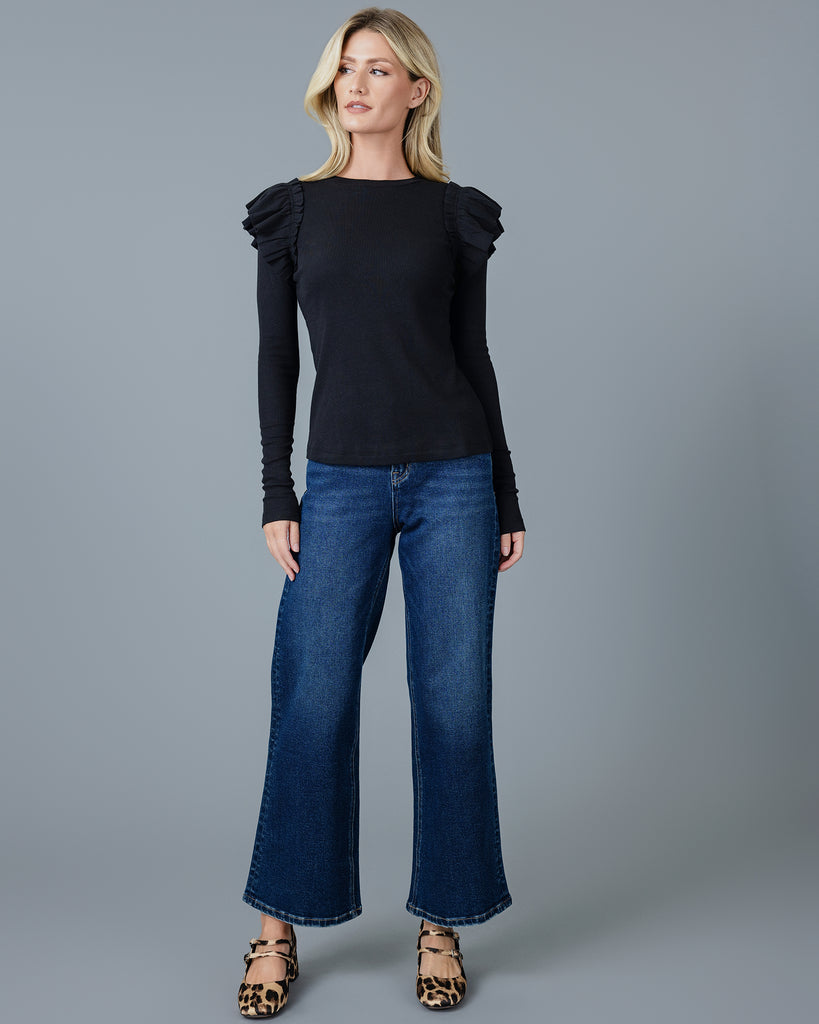 Woman in a black long sleeve t-shirt with double ruffles on shoulders