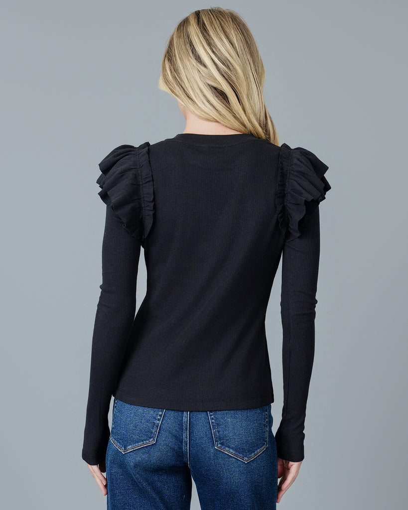 Woman in a black long sleeve t-shirt with double ruffles on shoulders