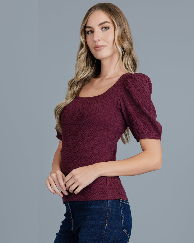 Woman in a plum colored short sleeve top with a scoop neck