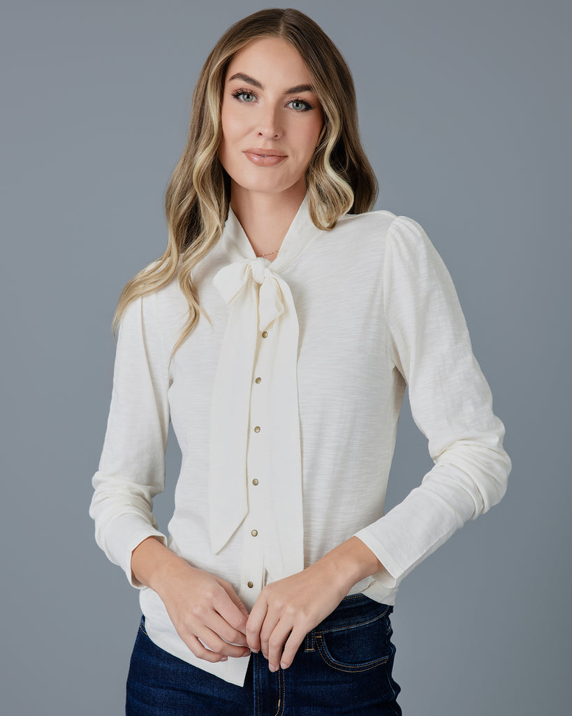 Woman in a white long sleeve knit buttondown with tie at neck