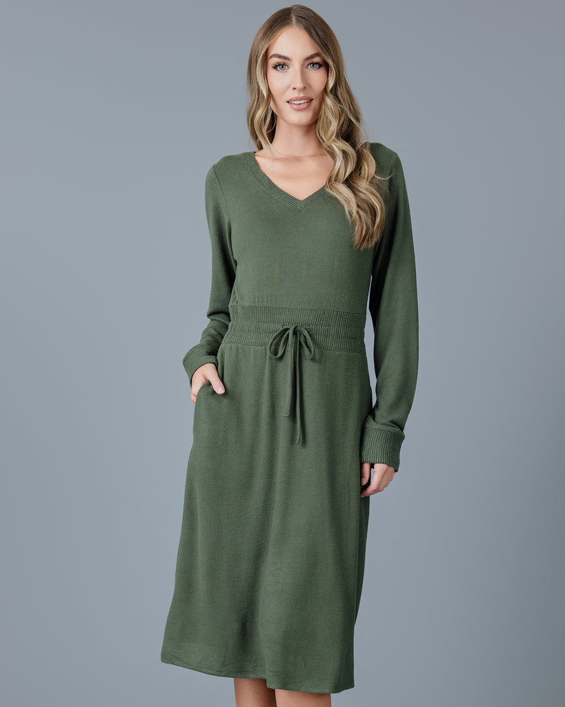 Woman in a green long sleeve, v-neck, midi-length sweater dress