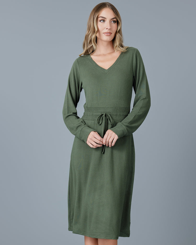 Woman in a green long sleeve, v-neck, midi-length sweater dress