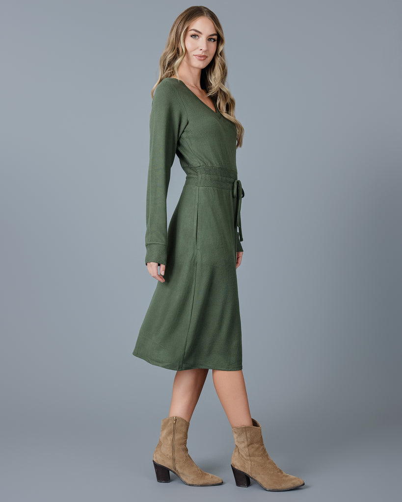 Woman in a green long sleeve, v-neck, midi-length sweater dress