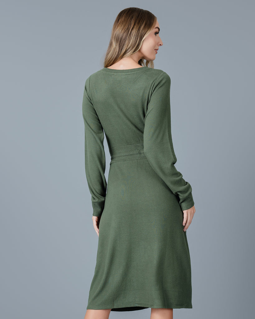 Woman in a green long sleeve, v-neck, midi-length sweater dress