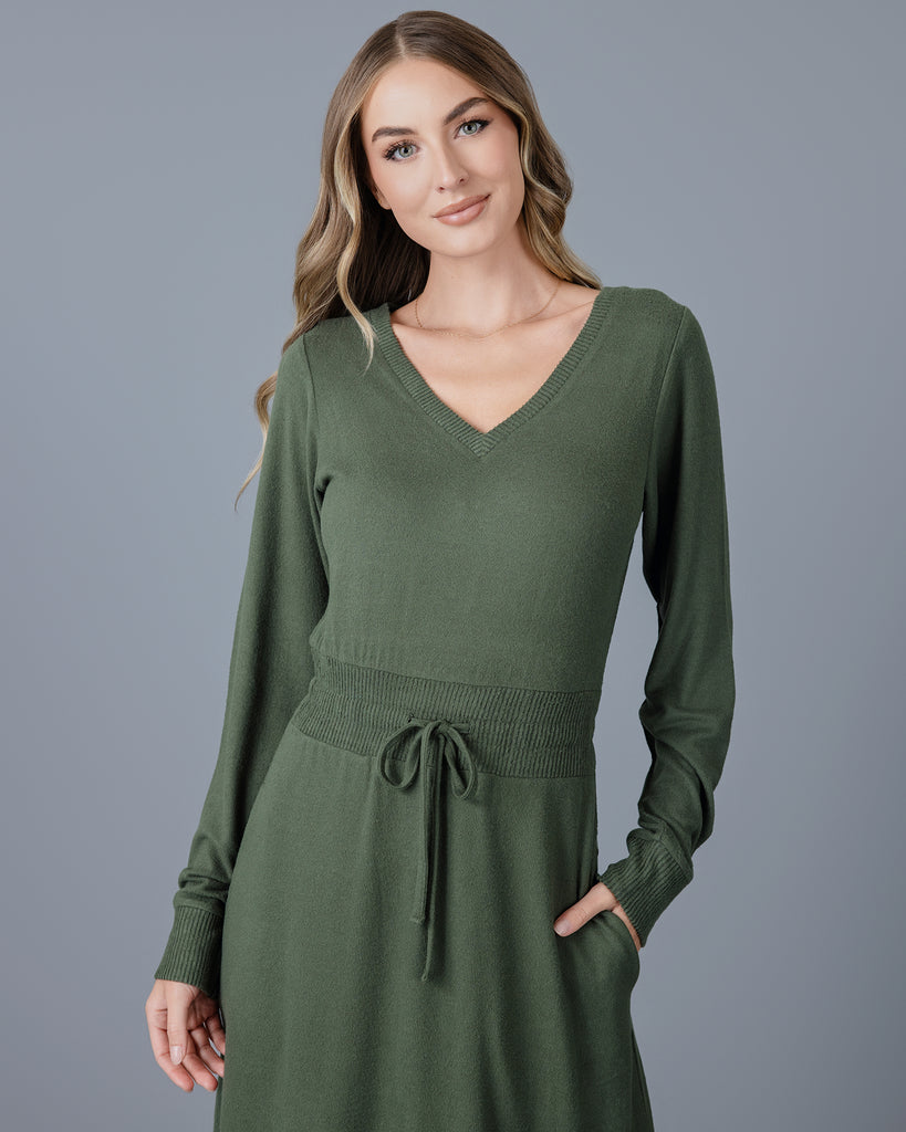 Woman in a green long sleeve, v-neck, midi-length sweater dress