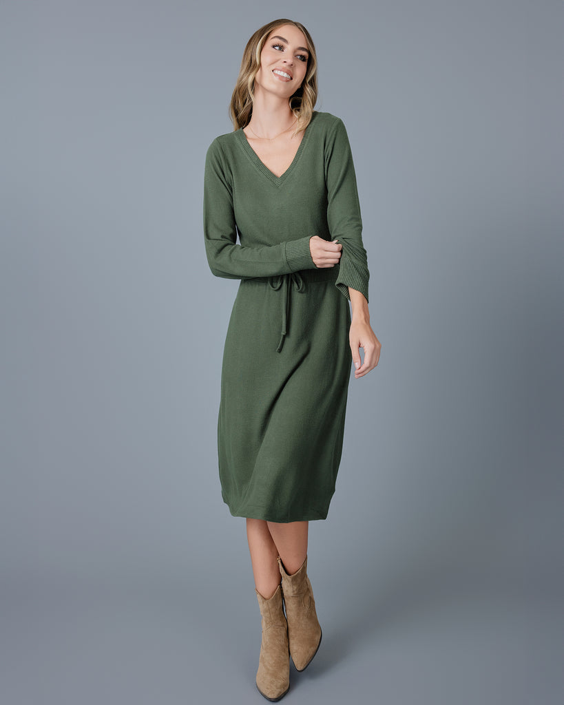 Woman in a green long sleeve, v-neck, midi-length sweater dress