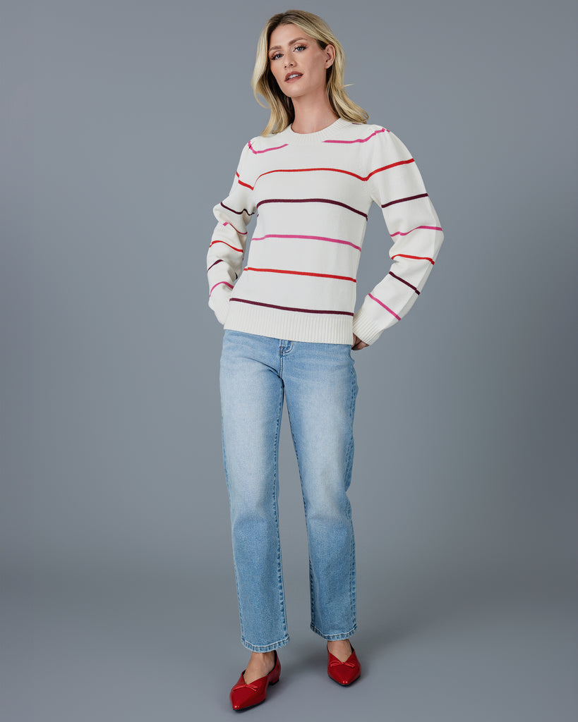 Woman in a white with red, white and purple striped long sleeve pullover sweater