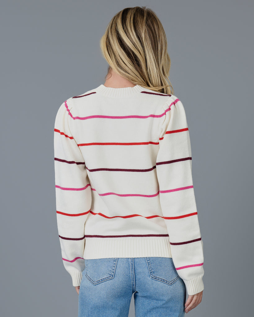 Woman in a white with red, white and purple striped long sleeve pullover sweater