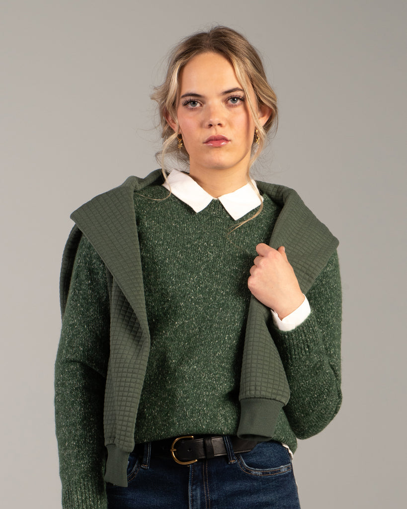 Model wearing a green speckled long sleeve crew neck pullover sweater.