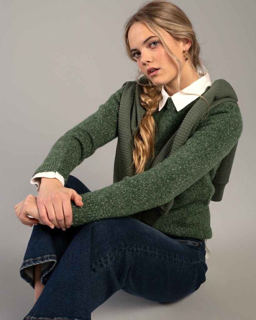 Model wearing a green speckled long sleeve crew neck pullover sweater.