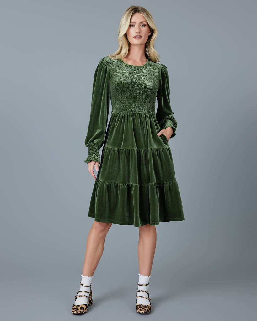 Woman in a green velvet long sleeve knee-length dress