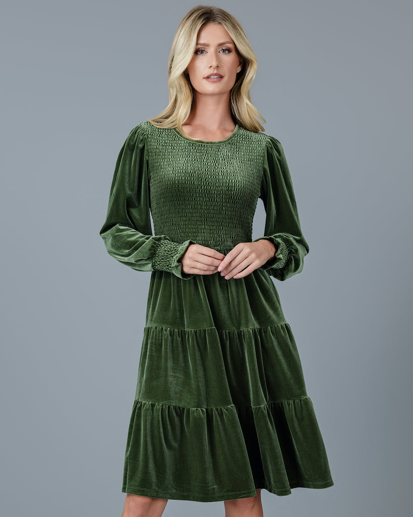 Woman in a green velvet long sleeve knee-length dress