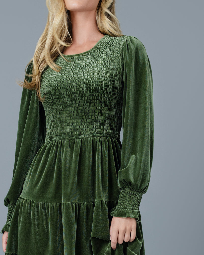 Woman in a green velvet long sleeve knee-length dress