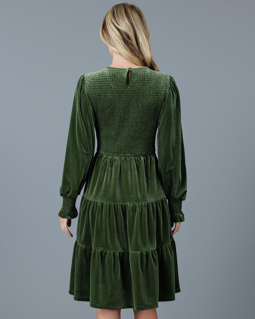 Woman in a green velvet long sleeve knee-length dress