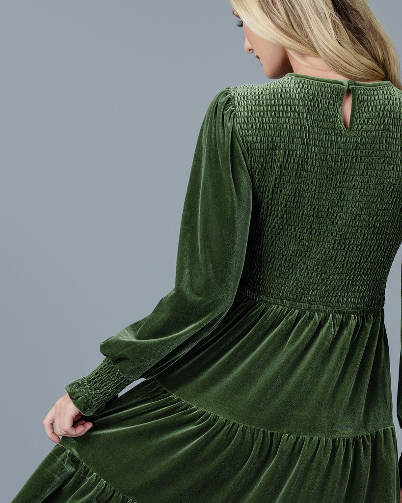 Woman in a green velvet long sleeve knee-length dress