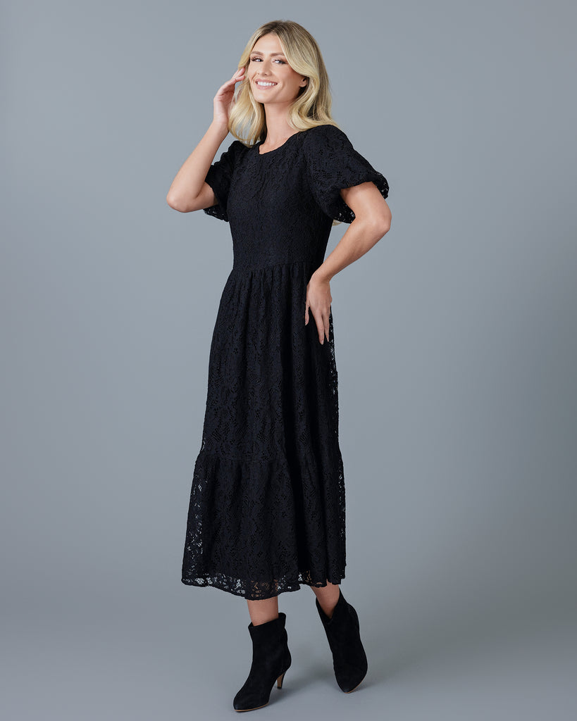 Woman in a black short sleeve midi-length lace dress