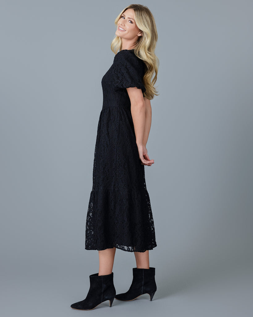 Woman in a black short sleeve midi-length lace dress