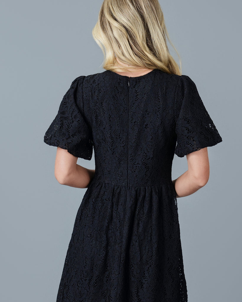 Woman in a black short sleeve midi-length lace dress