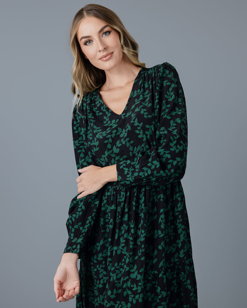 Model wearing a knee-length floral dress with long sleeves