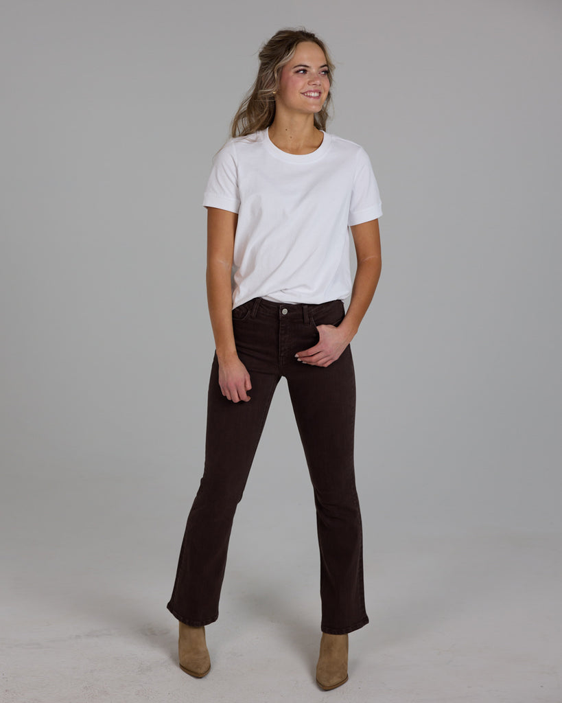 Model wearing dark brown bootcut ankle length denim jeans.