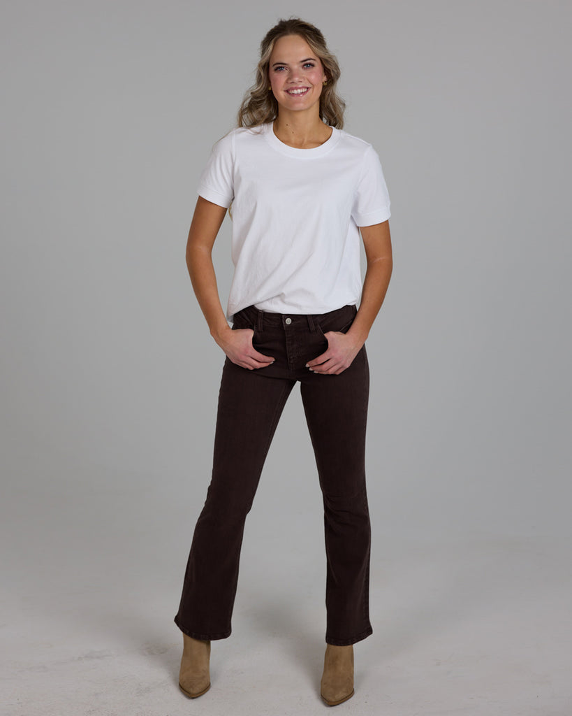 Model wearing dark brown bootcut ankle length denim jeans.