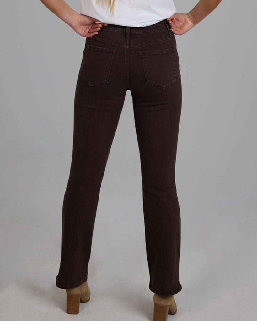 Model wearing dark brown bootcut ankle length denim jeans.