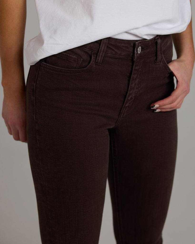 Model wearing dark brown bootcut ankle length denim jeans.