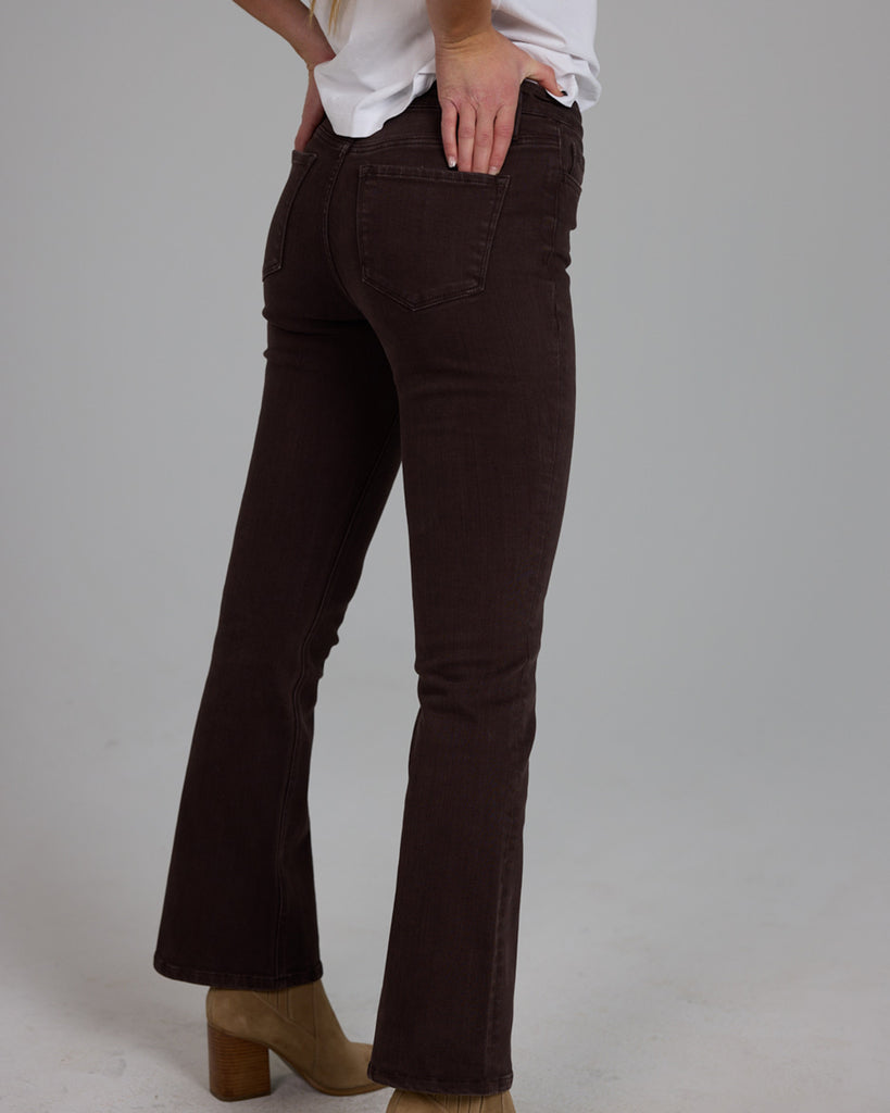 Model wearing dark brown bootcut ankle length denim jeans.