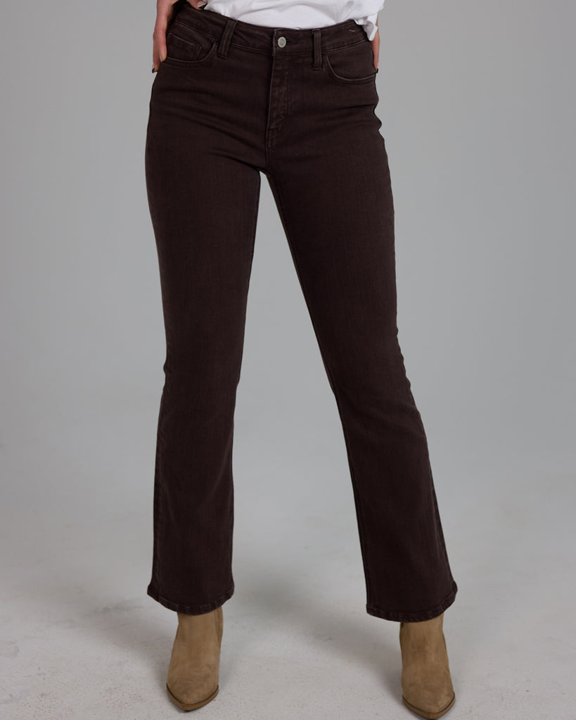 Model wearing dark brown bootcut ankle length denim jeans.