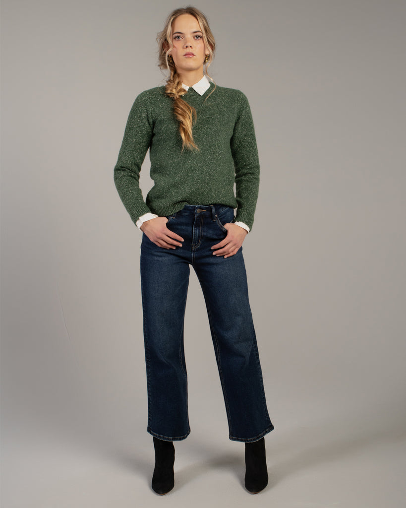 Model wearing dark blue wide leg ankle length denim jeans.