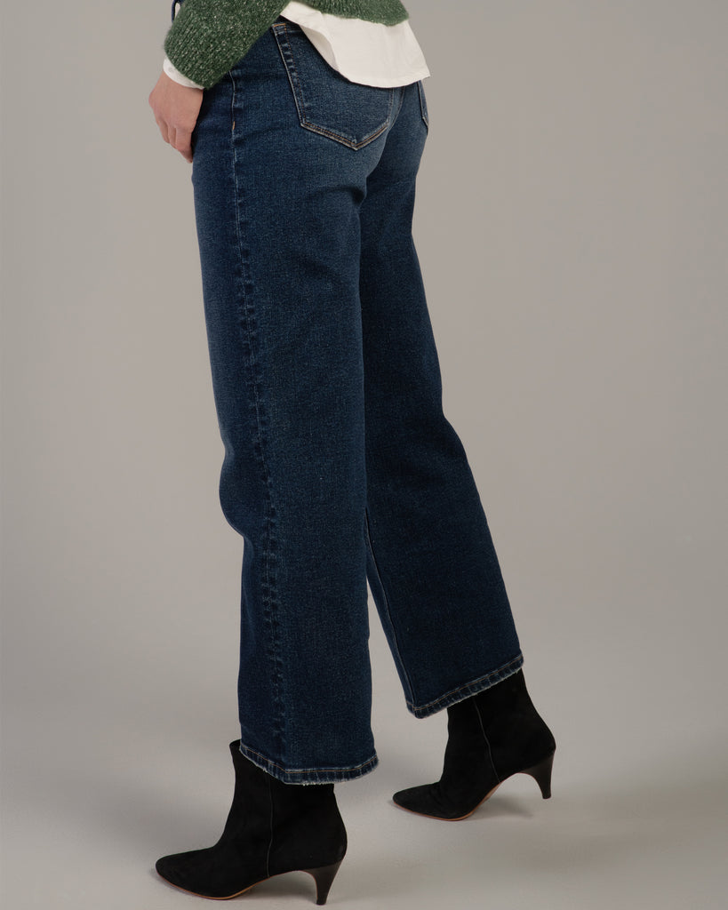 Model wearing dark blue wide leg ankle length denim jeans.