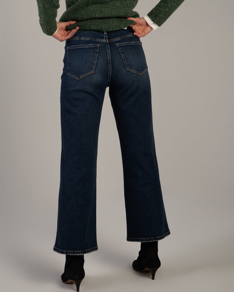 Model wearing dark blue wide leg ankle length denim jeans.