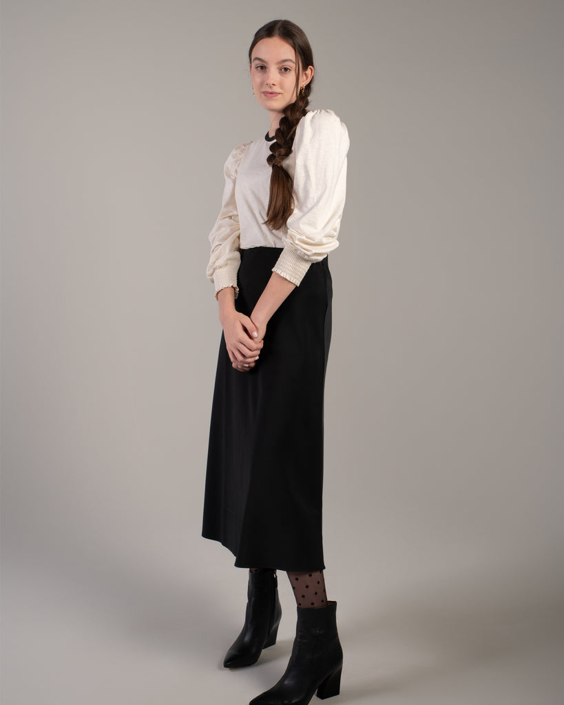 Woman in a white blouse with black detail around neckline