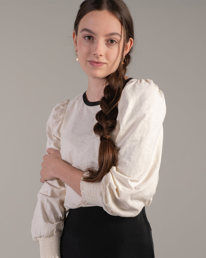 Woman in a white blouse with black detail around neckline